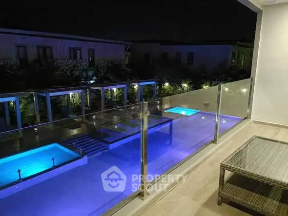 Luxurious night view of illuminated pool from modern balcony.