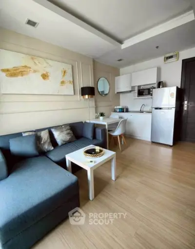 Modern living room with open kitchen, stylish decor, and cozy seating in a contemporary apartment.