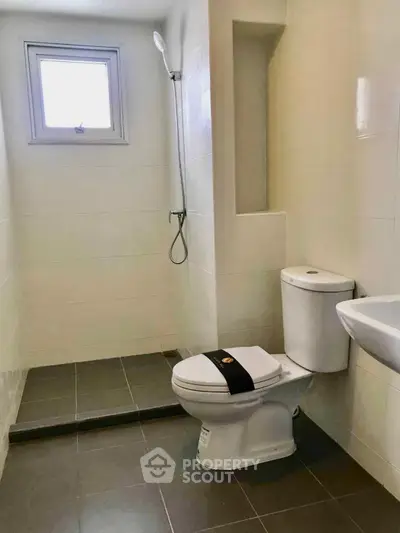 Modern bathroom with sleek design, featuring a shower, toilet, and sink in a bright, tiled space.