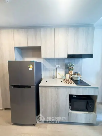 Modern kitchen with sleek cabinetry, built-in appliances, and stylish backsplash in a contemporary apartment.