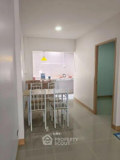 Modern dining area with open kitchen layout and stylish lighting in a cozy apartment.