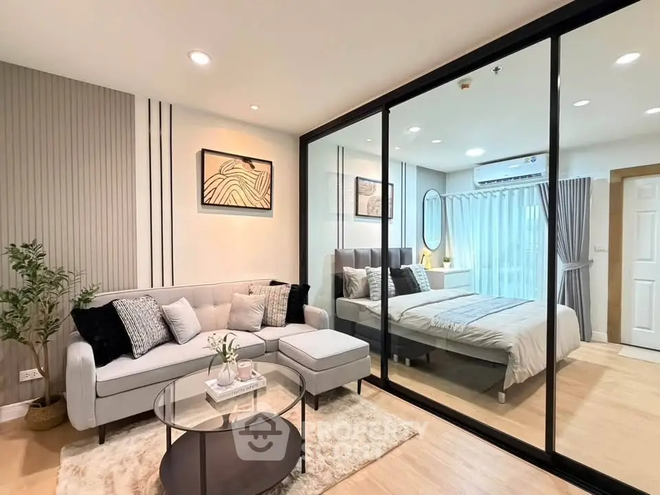 Modern open-plan living room and bedroom with stylish decor and glass partition.