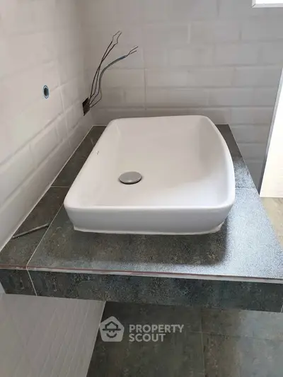 Modern bathroom sink with sleek design and tiled backsplash.