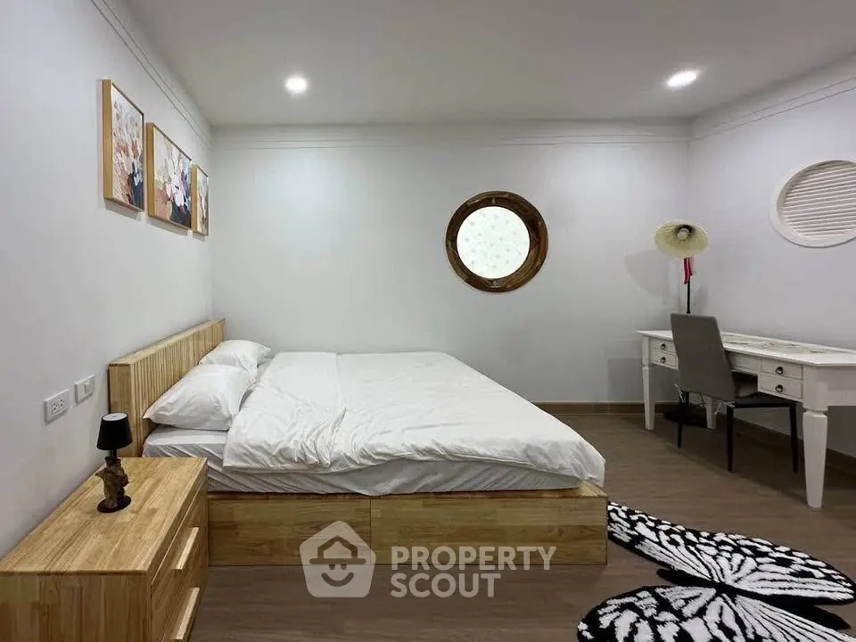 Modern bedroom with wooden furniture and unique circular window design.