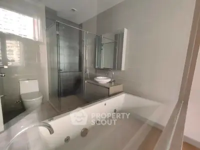 Modern bathroom with jacuzzi tub and glass shower in luxury apartment.