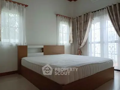 Spacious bedroom with natural light and elegant curtains