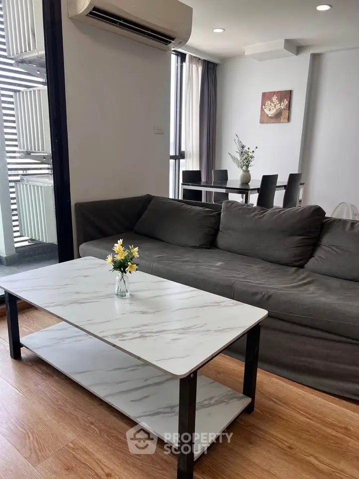 Modern living room with sleek furniture and dining area, featuring a stylish marble coffee table and cozy ambiance.