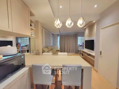 Modern living room with open kitchen, stylish lighting, and cozy seating area.