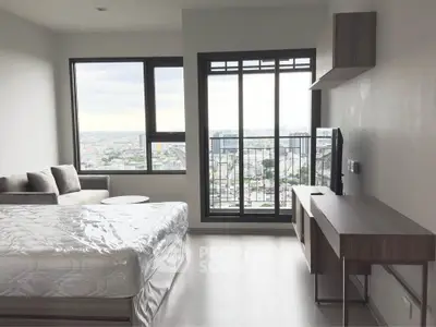 Modern bedroom with large window offering stunning city view, featuring stylish furniture and natural light.
