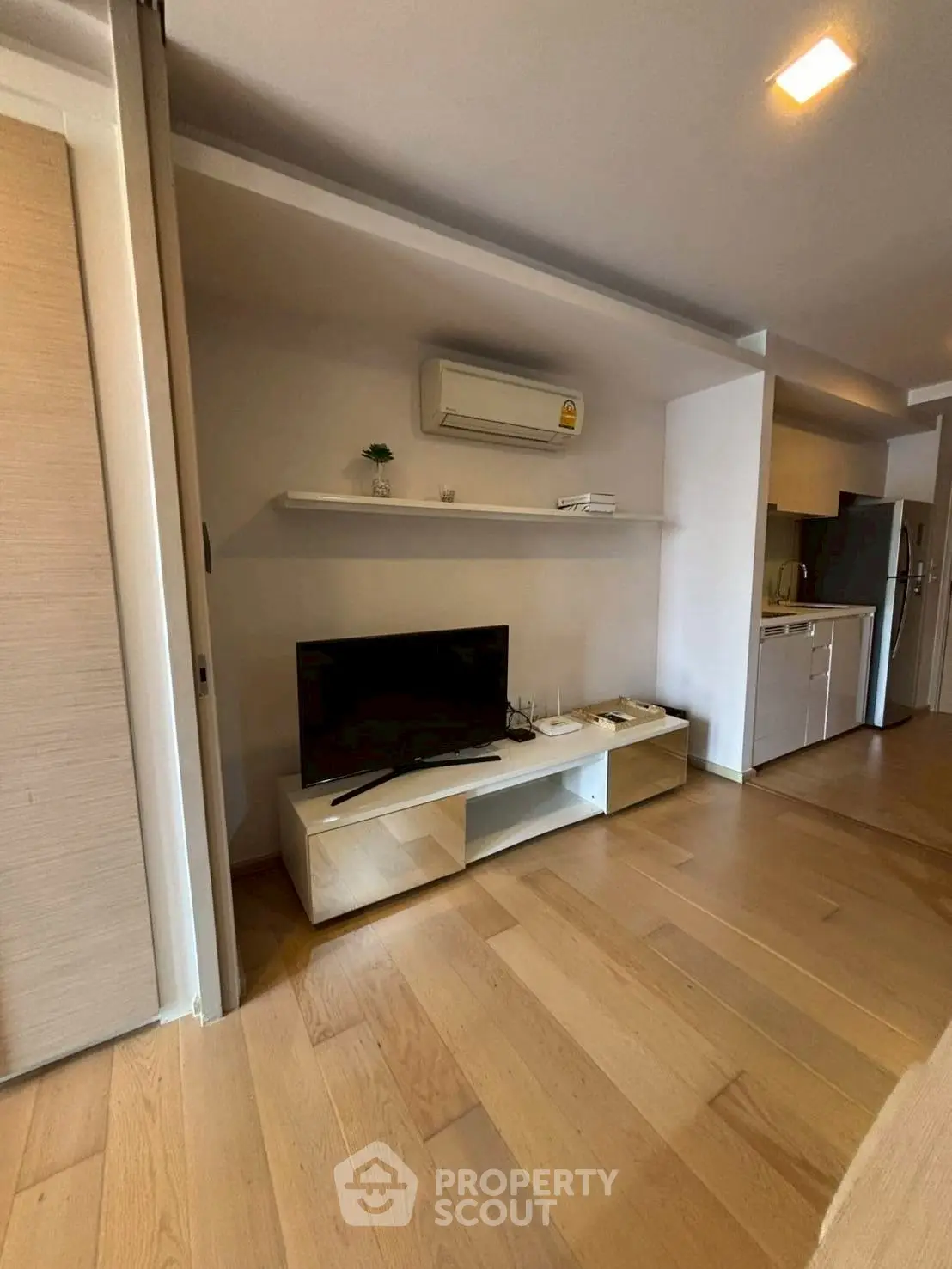 Modern living room with wooden flooring and sleek TV unit, perfect for cozy entertainment.