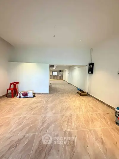 Spacious open-plan interior with tiled flooring and ample natural light, ideal for versatile living arrangements.