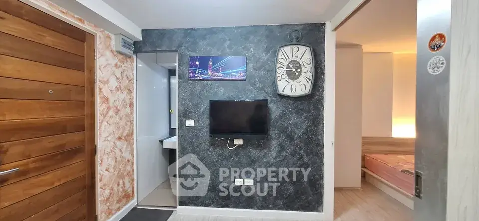 Modern apartment interior with stylish wall clock and TV, showcasing a cozy bedroom entrance.