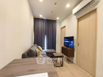 Modern living room with sleek furniture and wall-mounted TV in a cozy apartment setting.
