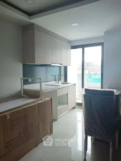 Modern kitchen with sleek cabinetry and large window for natural light.