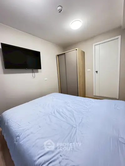 Cozy bedroom with modern TV and sleek wardrobe, perfect for relaxation.