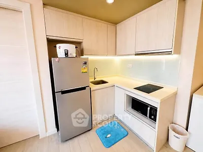 Modern compact kitchen with sleek cabinetry and appliances in a cozy apartment setting.