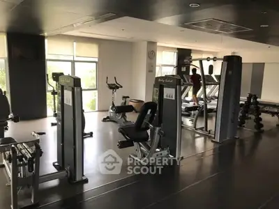 Spacious gym with modern fitness equipment and large windows for natural light.