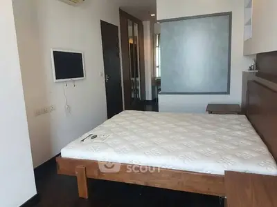 Spacious bedroom with modern furnishings and wall-mounted TV in a stylish apartment.