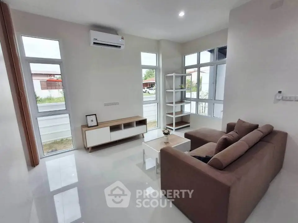 Modern living room with large windows and cozy sofa in a bright, minimalist design.