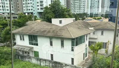 Charming suburban house with tiled roof surrounded by lush greenery and modern high-rise buildings.