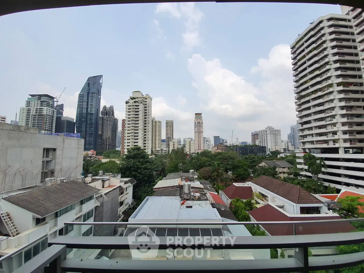 Stunning cityscape view from a high-rise balcony overlooking urban skyline and lush greenery.