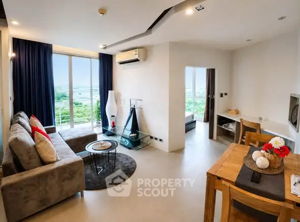 Modern living room with large windows and stylish decor in a high-rise apartment.