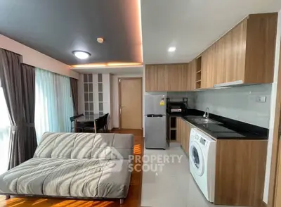 Modern open-layout living room with kitchen, featuring sleek appliances and stylish decor.