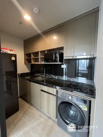 Modern kitchen with sleek cabinets, washing machine, and black marble countertop