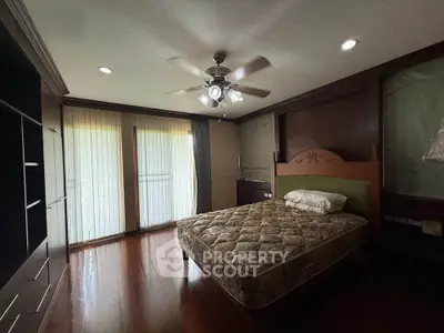 Spacious bedroom with elegant wooden flooring and ceiling fan