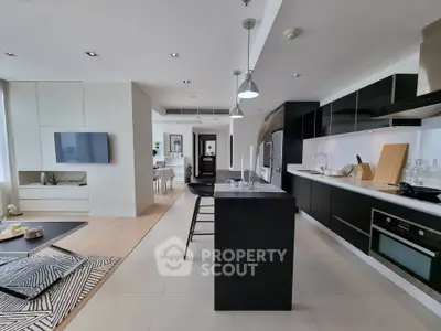 Modern open-layout kitchen with sleek black and white design, featuring a breakfast bar and integrated appliances.