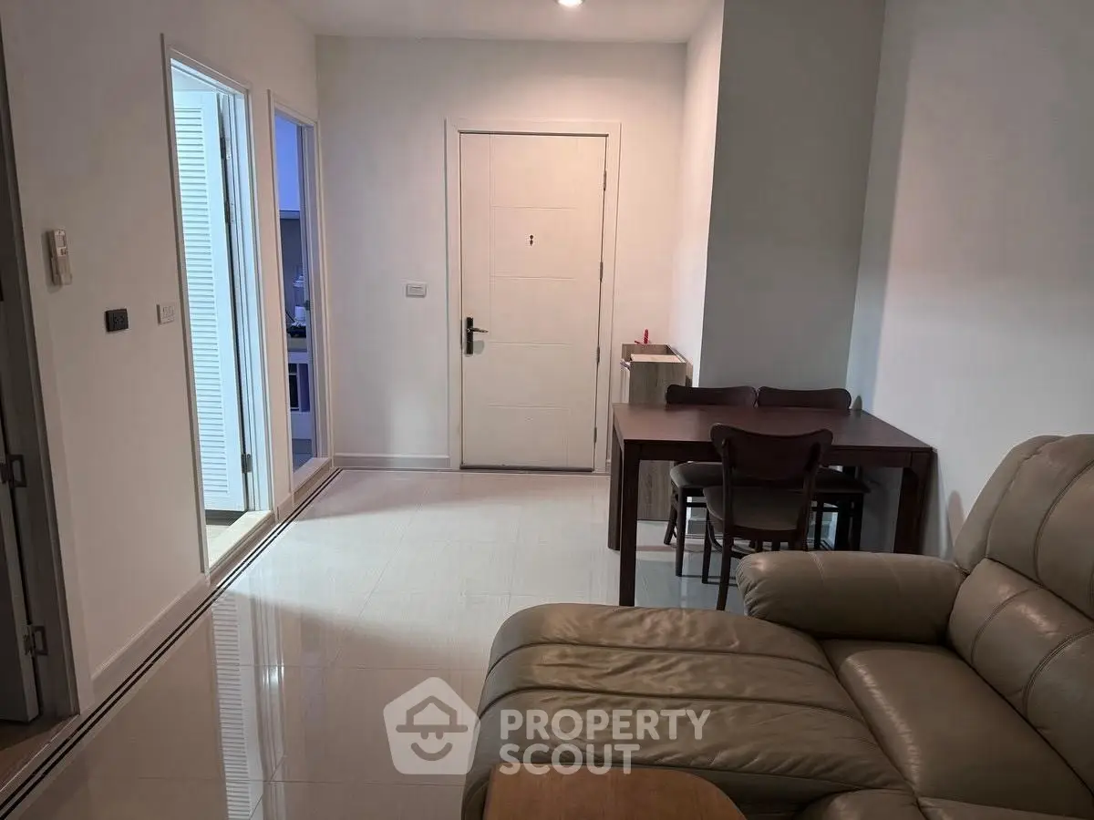 Cozy living room with leather sofa and dining table near entrance