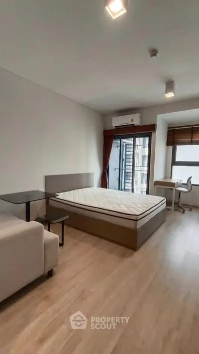 Spacious bedroom with modern furnishings and large window offering natural light.