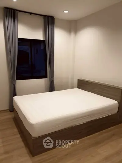Modern minimalist bedroom with wooden flooring and large window