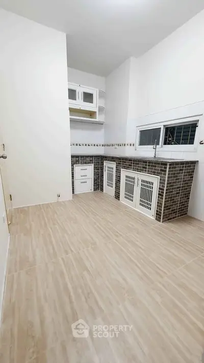 Spacious kitchen with modern cabinetry and tiled backsplash in a bright, minimalist design.