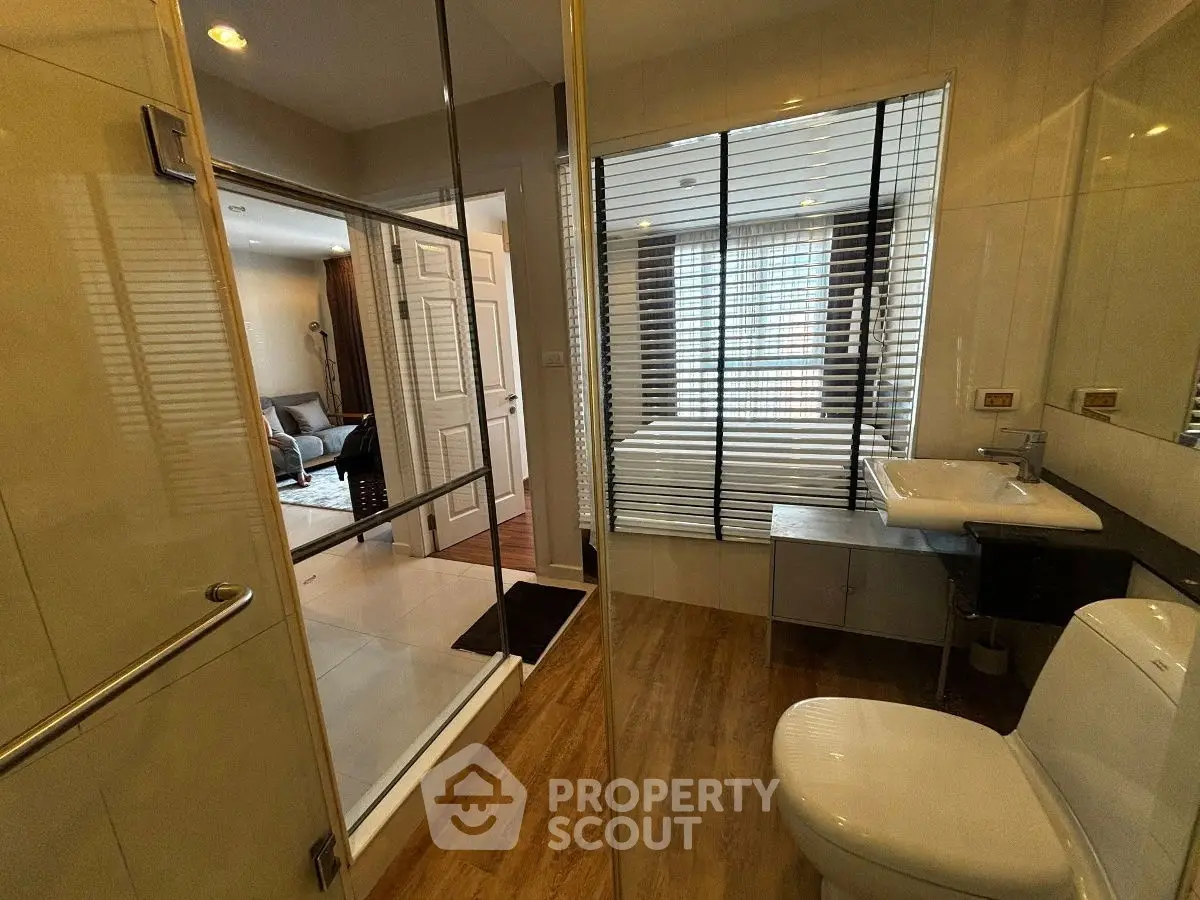 Modern bathroom with glass partition and view into bedroom