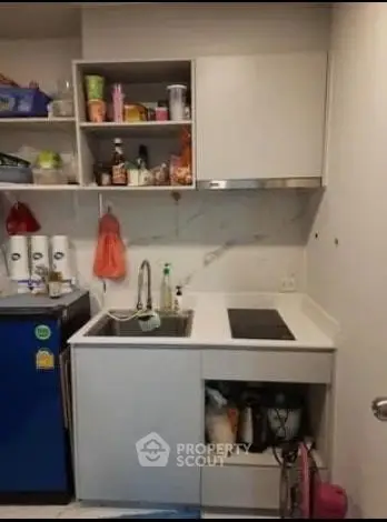 Compact kitchen with modern appliances and open shelving in a cozy apartment.