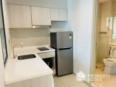 Modern kitchen with sleek cabinetry and adjacent bathroom in a stylish apartment.