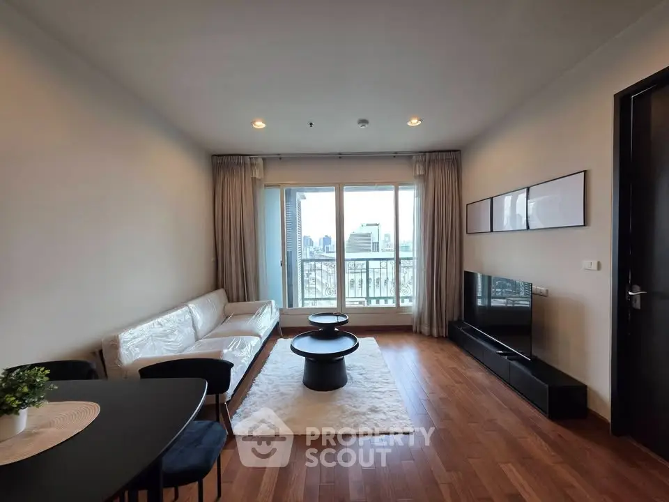 Modern living room with city view, hardwood floors, and stylish furniture in a high-rise apartment.