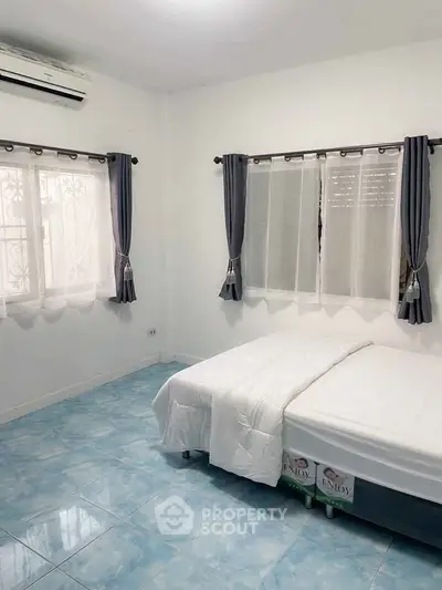 Bright bedroom with blue tiled floor and air conditioning, featuring large windows and modern curtains.