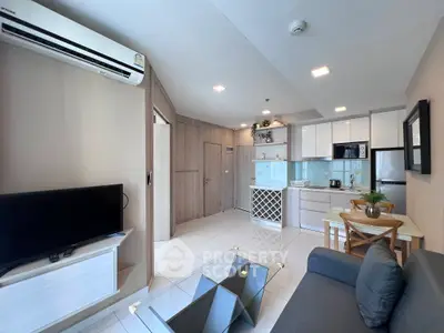 Modern open-layout living room and kitchen with sleek furniture and bright lighting.