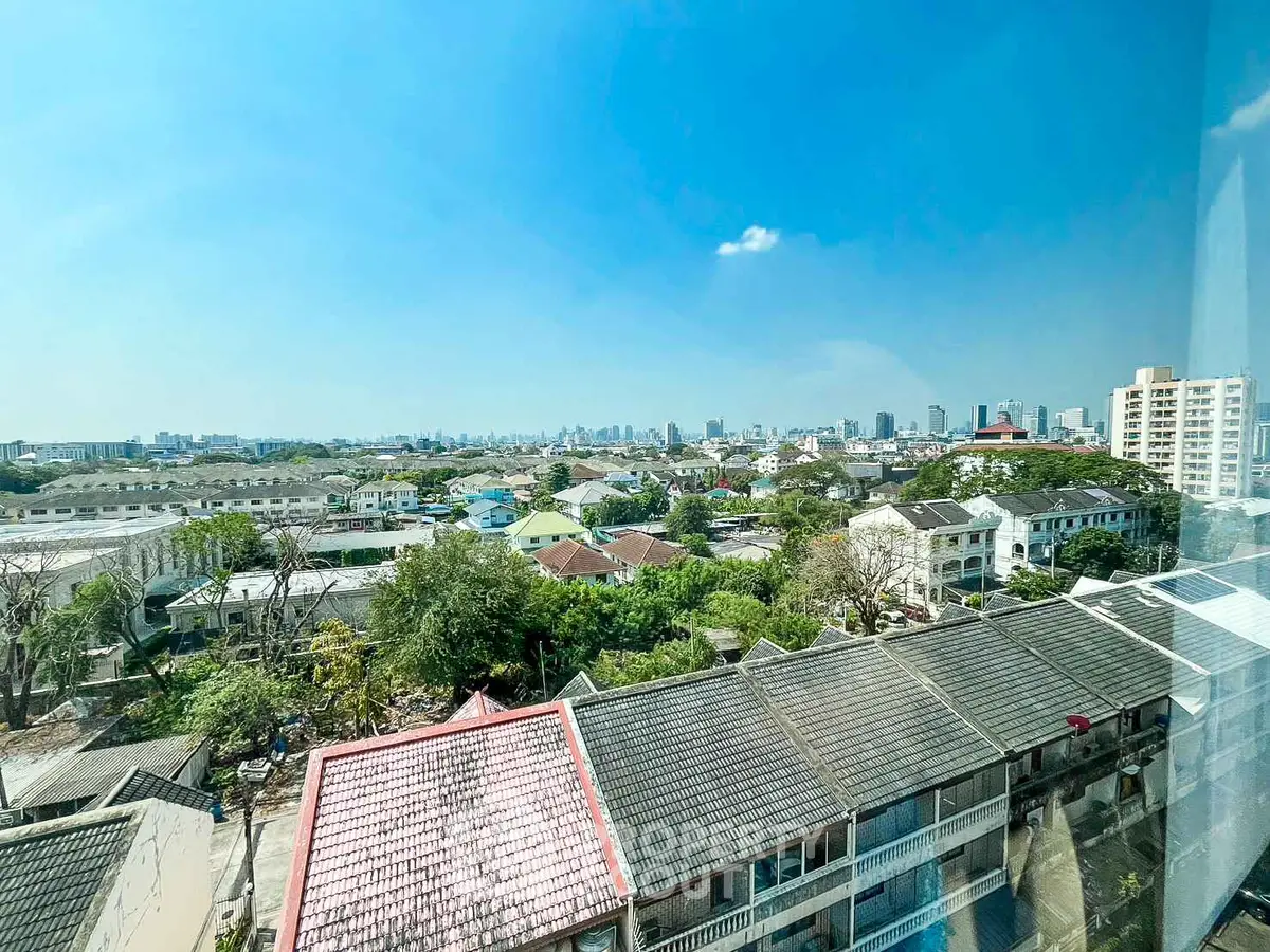Stunning cityscape view from high-rise apartment window showcasing urban skyline and residential rooftops.