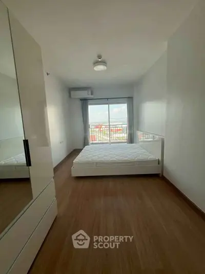 Spacious bedroom with large window and balcony access, featuring modern minimalist design and ample natural light.