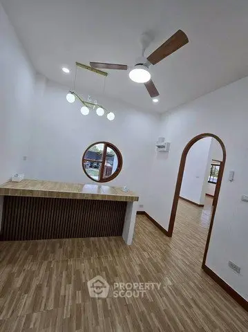 Modern interior with wooden flooring, ceiling fan, and stylish lighting in a spacious room.