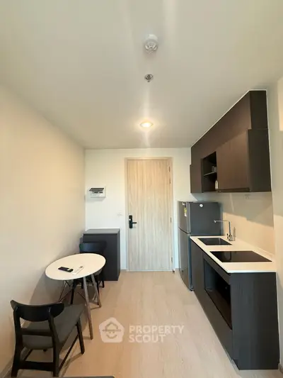 Modern compact kitchen with sleek cabinetry and dining area in a cozy apartment.