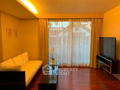 Elegant living room with hardwood floors, cozy sofa, and large TV, perfect for relaxation and entertainment.