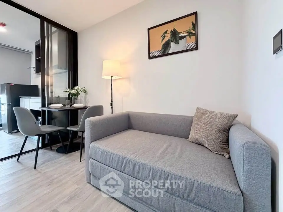 Modern living room with cozy gray sofa and stylish dining area in open layout apartment.