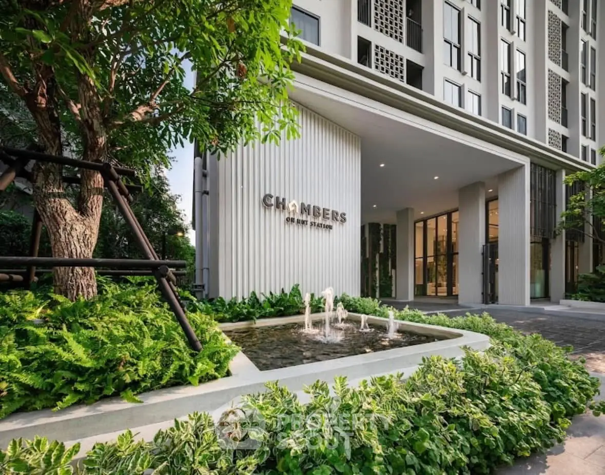 Modern building entrance with lush greenery and water feature at Chambers On Nut Station.