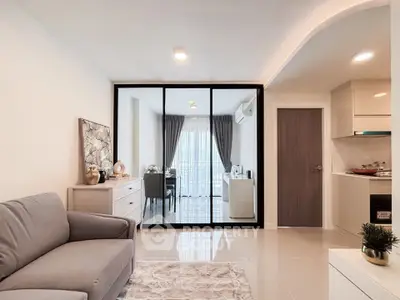 Modern living room with stylish decor and open kitchen layout, featuring elegant furniture and natural light.
