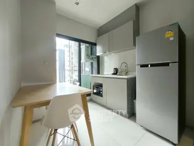 Modern kitchen with sleek appliances and dining area in a bright apartment.