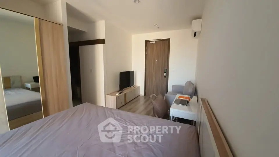 Modern bedroom with minimalist design, featuring a cozy bed, TV, and sleek furniture.